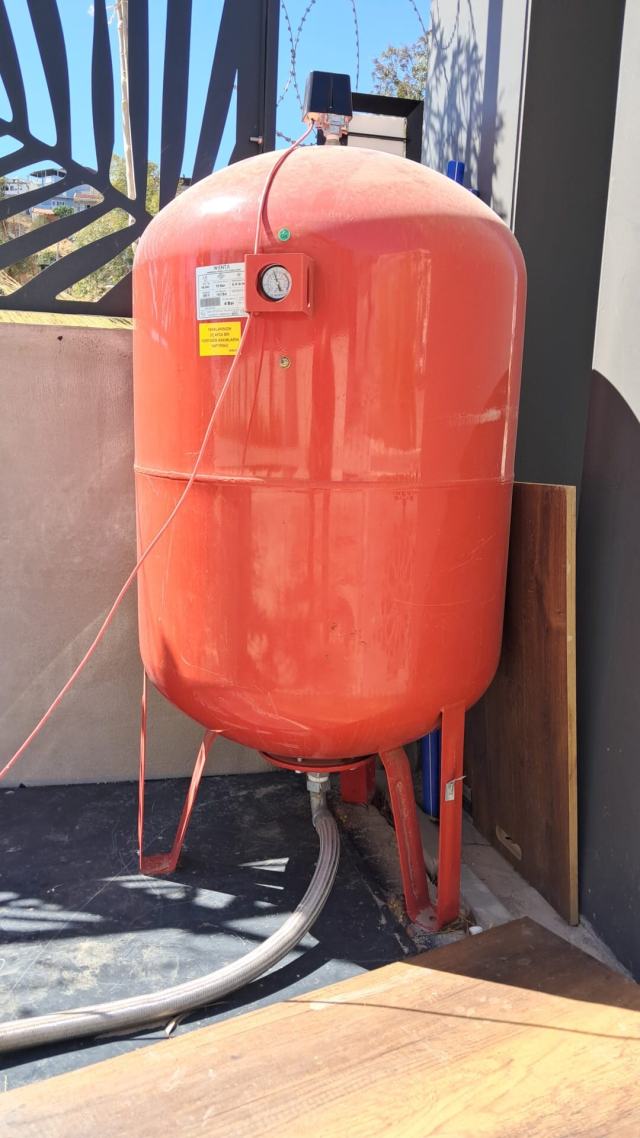 Kapalı devre tesisatta duvara bağlı kırmızı genleşme tankı