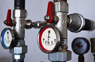 Kalorifer dairesinde kırmızı kollu vanalar ve sıcaklık göstergeleri